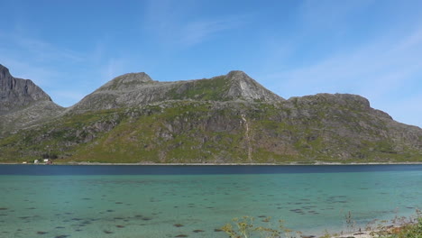 little beach in a fiord in norway with big mountains behind