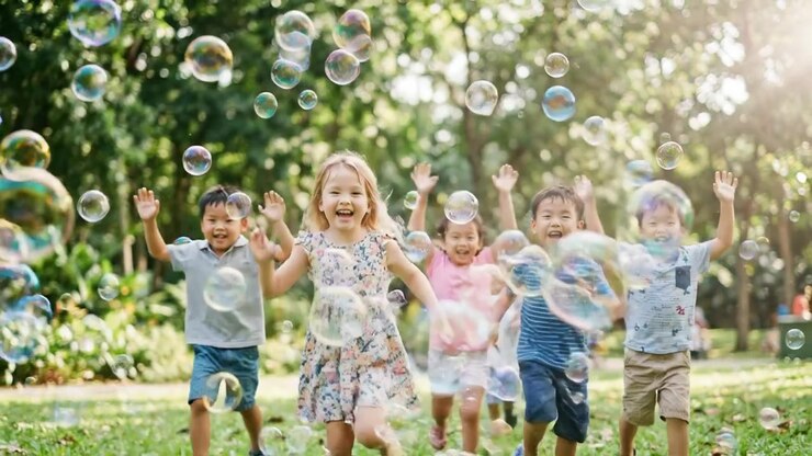 Gruppo di bambini felici che corrono tra le bolle in un parco
