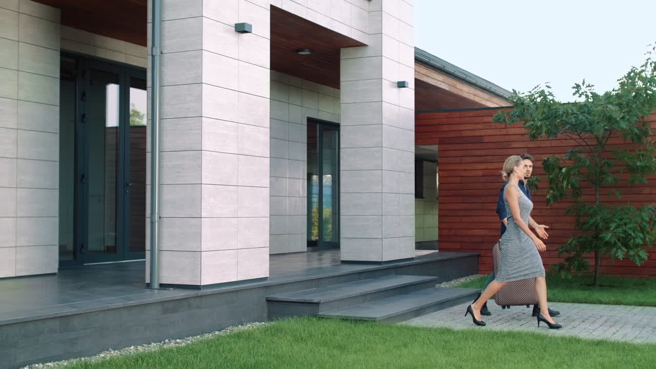 una pareja rica sale de apartamentos de lujo. gente hermosa de pie afuera.