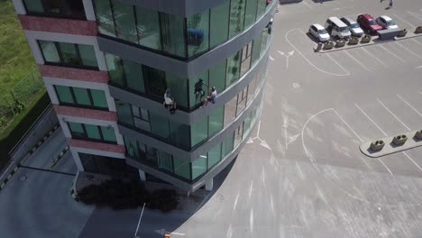antena de retroceso lento sobre escaladores industriales que cuelgan para limpiar las ventanas de los edificios de oficinas