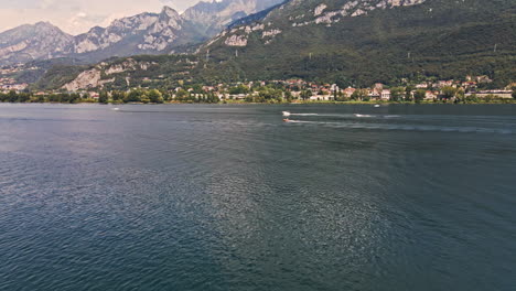 beautiful lake como with boats sailing during sunny day of summer in northern italy - aerial drone shot