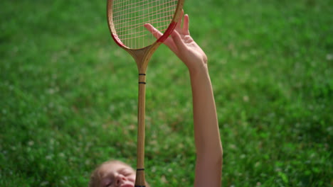 closeup badminton racket in hands of smiling joyful girl lying on blanket.