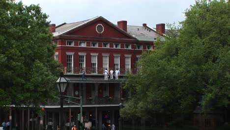 a mediumshot of repairmen standing on the balcony of an old brick building doing repairs