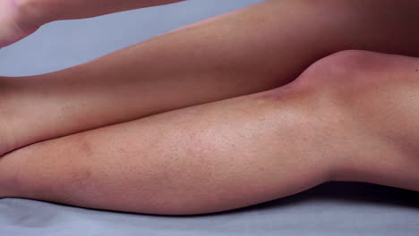 close-up of an individual trying to give herself a massage by slowly caressing her knees down to her legs in a downward and upward motion