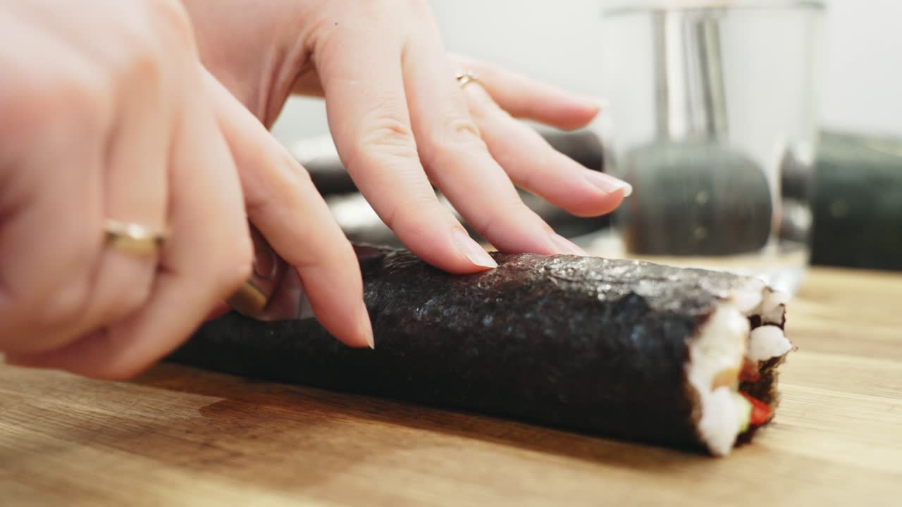Žena krájí sushi k večeři nožem, zblízka.
