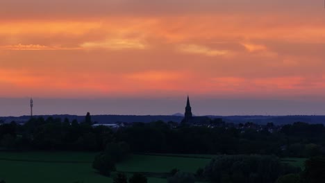 Sunset-of-colour-lights-up-the-evening-sky,-Church-spire-silhouette
