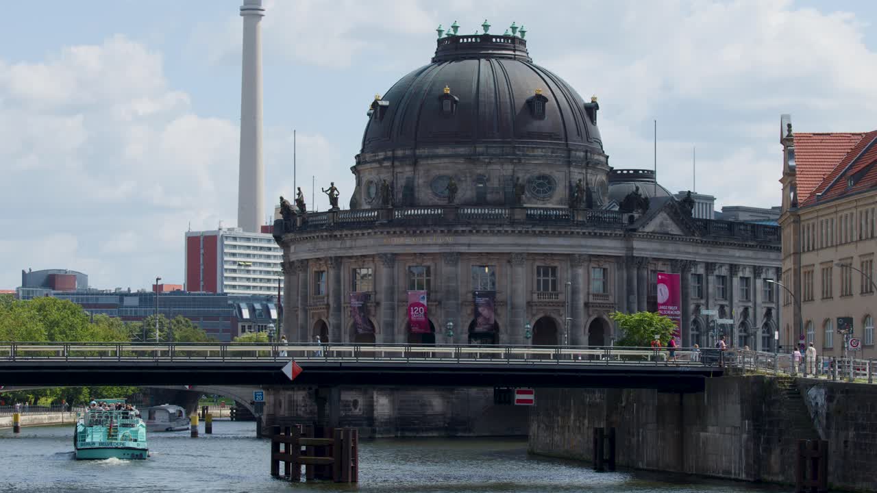 Tourist boat glides under bridge by Bode Museum, sunny day, steady wide shot, Berlin