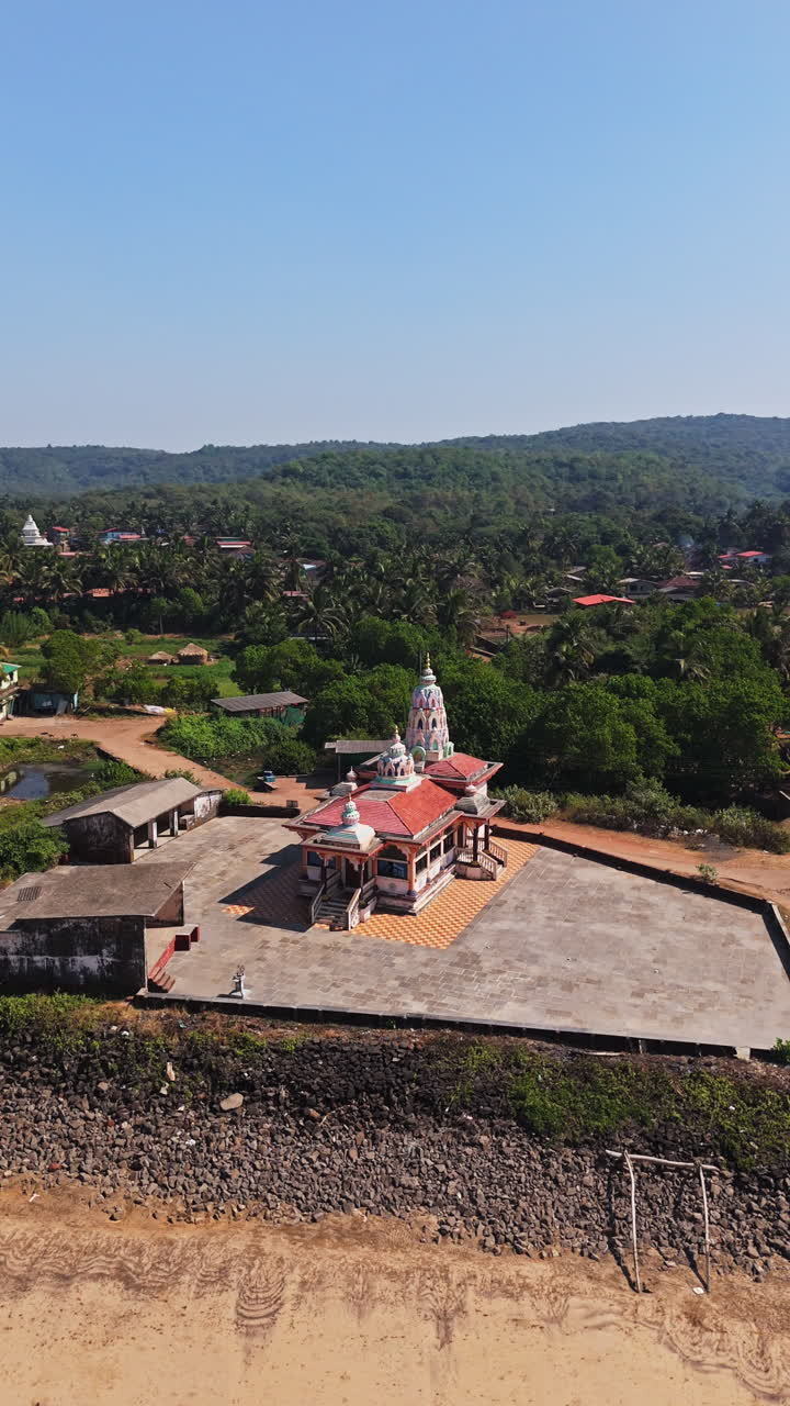 Vertical drone shot circling a Hanuman Mandir Hindu temple, in Guhagar, India