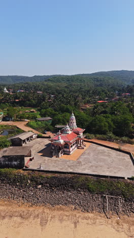 vertical drone shot circling a hanuman mandir hindu temple, in guhagar, india