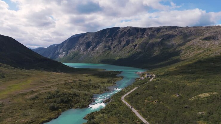 Una vista aerea mozzafiato di un paesaggio scenografico con un fiume, una strada e montagne a Innlandet vicino a Besseggen, Norvegia