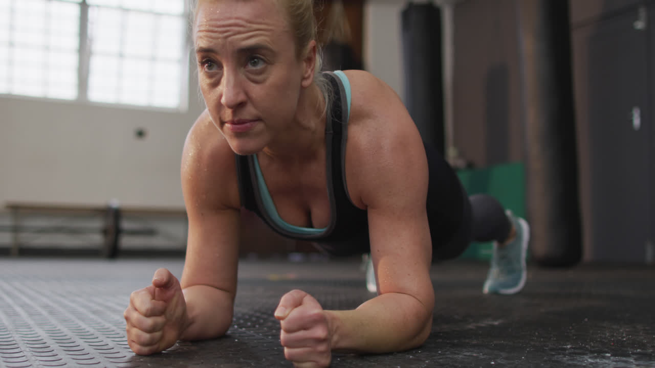 un primer plano de una mujer caucásica en forma haciendo ejercicios de tabla en el gimnasio.