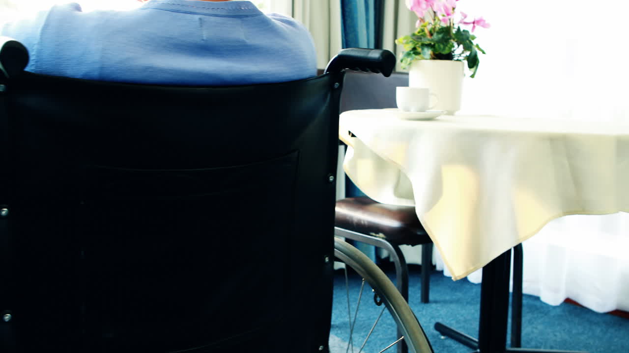 Seniorin im Rollstuhl blickt aus dem Fenster