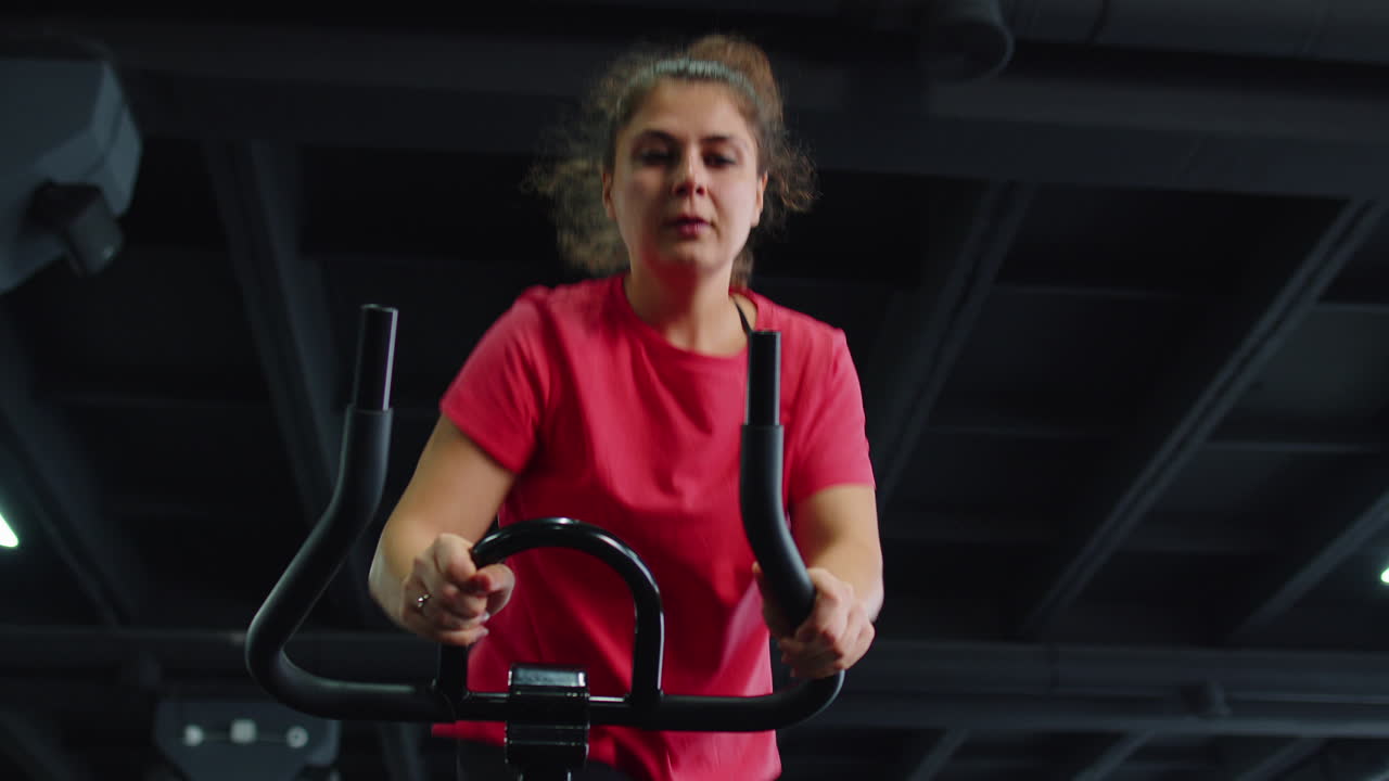 Gruppo di ragazze esegue un allenamento cardio aerobico su cyclette, allenamento ciclistico.