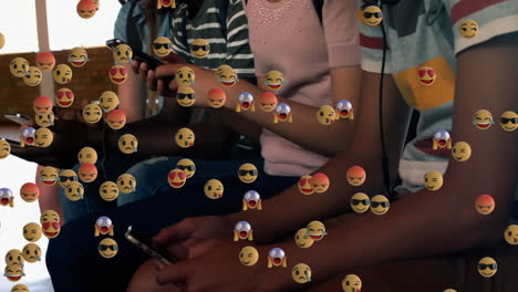 múltiples emojis de cara flotando contra un grupo de estudiantes que usan teléfonos inteligentes