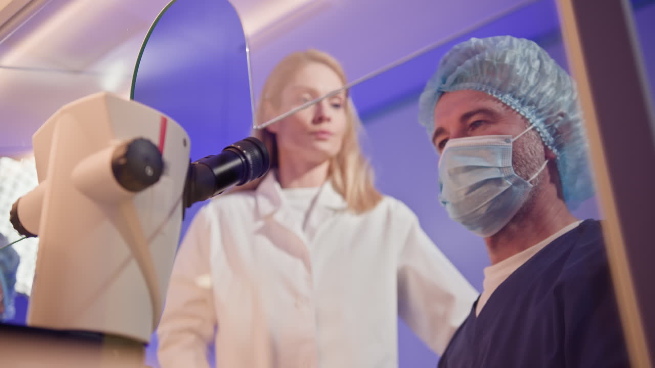 profesionales médicos que examinan bajo el microscopio