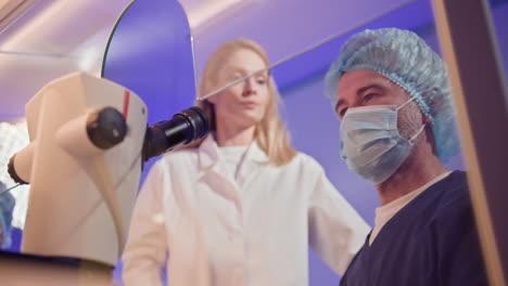 profesionales médicos que examinan bajo el microscopio