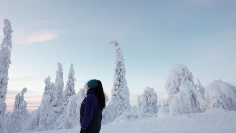 girl walking and exploring winter wonderland landscape with huge snow covered trees in lapland, finland, arctic circle