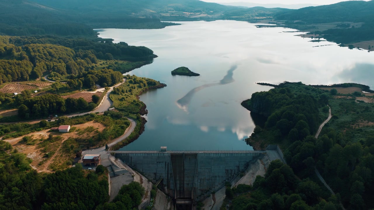 Aerial View of a Concrete Dam and Reservoir Surrounded by Lush Green Forest