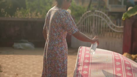 a woman in a floral dress is cleaning a floral fabric with a soap spray bottle