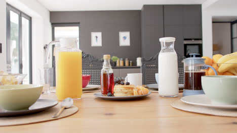 Close-up-of-table-with-breakfast-food-and-drinks-in-kitchen,-slow-motion