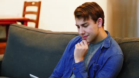 hombre sentado en el sofá y usando una tableta digital en la sala de estar