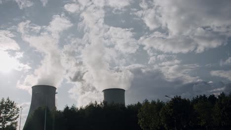 cooling towers in power plant generating steam against cloudy sky