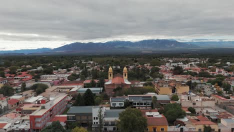 Aerial-drone-shot-of-residential-houses-in-cafayate-town-of-Argentina-with-Andean-Cordillera-Mountain-Range-in-Background