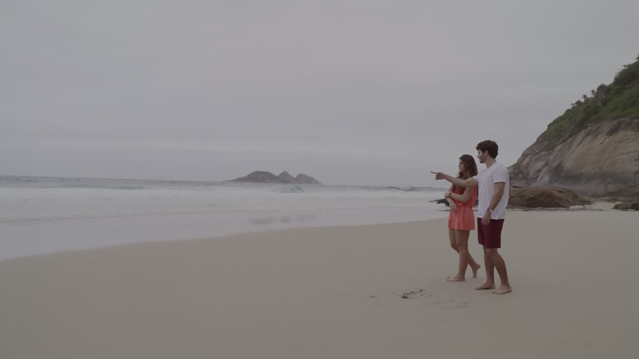 Couple on a Sandy Beach Looking at the Ocean