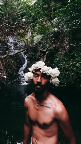 man with flower crown by waterfall in the forest