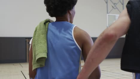 Diverse-male-basketball-team-training-with-male-coach-in-indoor-court,-in-slow-motion