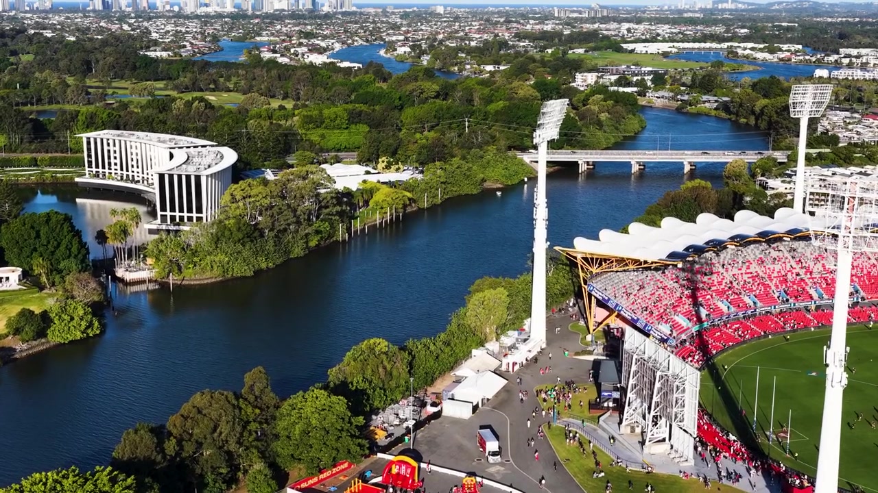 Ripresa aerea con drone che mostra una moderna arena sportiva accanto a un fiume serpeggiante di giorno