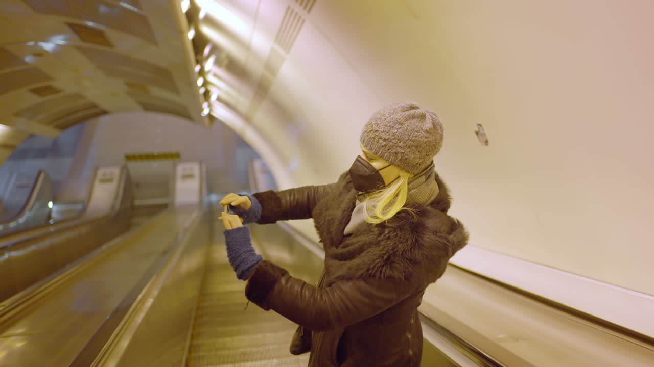 Woman on escalator taking photos in a tunnel