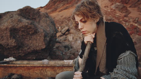 woman sitting by campfire in dystopian world