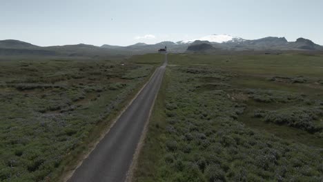 Road-leading-to-historical-church-in-Iceland,-Ingjaldshóll-church-on-hill