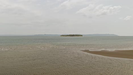 aerial drone shot flying towards alingkakajaw island - surigao del norte, philippines on a cloudy day