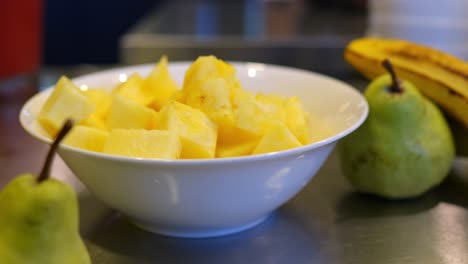 cuenco lleno de piña fresca y sabrosa junto a las peras