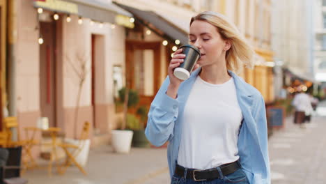 Mujer-Feliz-Disfrutando-De-Una-Bebida-Caliente-De-Café-Por-La-Mañana-Y-Sonriendo-Relajándose,-Tomando-Un-Descanso-En-Las-Calles-De-La-Ciudad