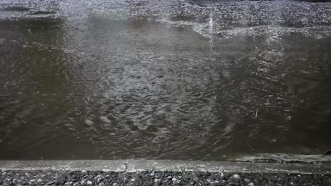static close-up shot of water flowing over a street in the metropolitan area of mexico city after a storm with hail
