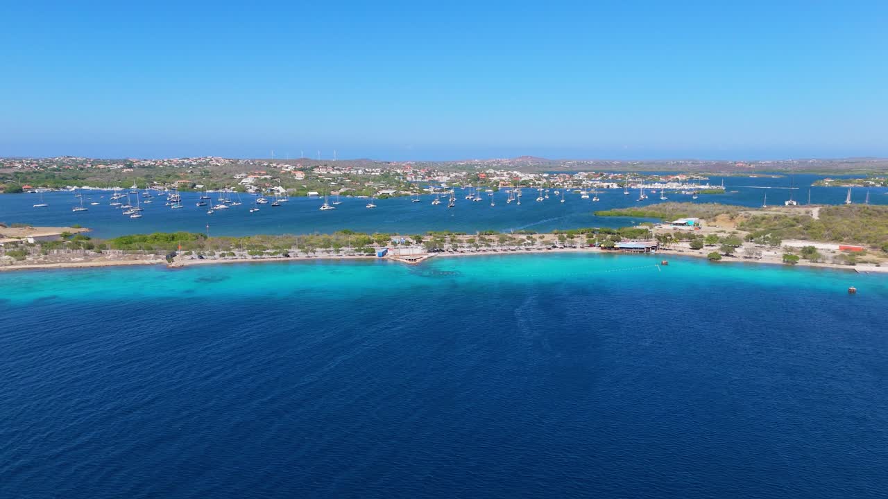 Aerial view of Caracasbaai Beach, Curacao, clear blue waters and sandy coastline surrounded by lush greenery by Spanish waters