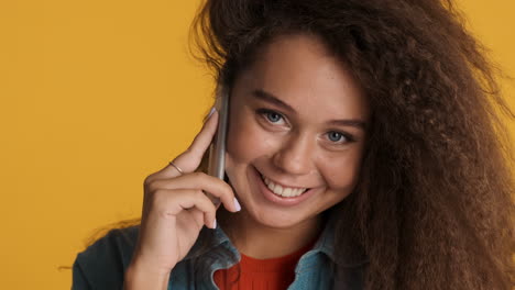 una mujer caucásica de cabello rizado llamando por teléfono.