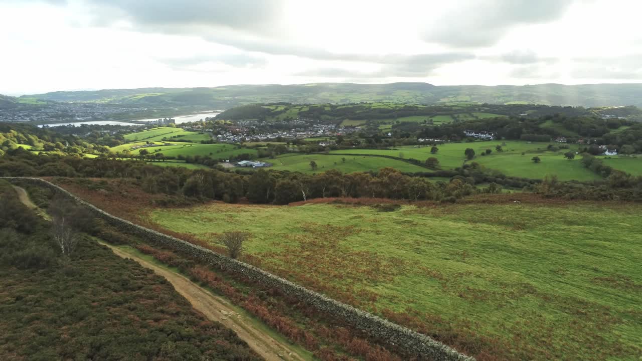 Sunbeams moving across overcast British agricultural rural village countryside morning aerial reverse right orbit view