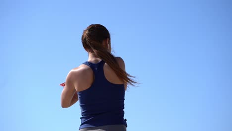 屋外で腕を伸ばしているスポーツの女の子の後ろの景色