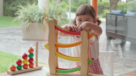 niña jugando con la rampa de carreras de coches - empujando coches de colores posicionándose en la parte superior de la rampa para seguir el curso de las pistas en diferentes colores