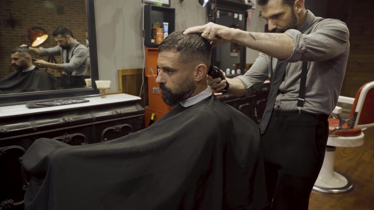 Barbiere che taglia i capelli a un cliente in una barberia - primo piano.