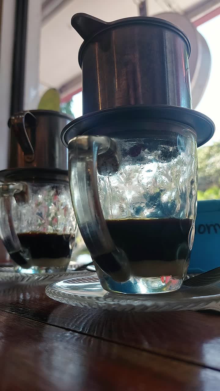 Low angle view of dripping Vietnamese coffee brewing in glass cups with drip filters called ca phe phin