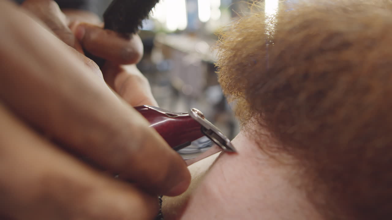barbero afeitando el cabello en el cuello del cliente con un cortador