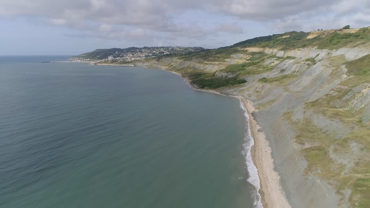 Backtracking aerial of Charmouth beach looking west along to Lyme Regis