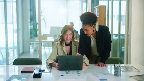 two businesswomen working on a laptop in an office