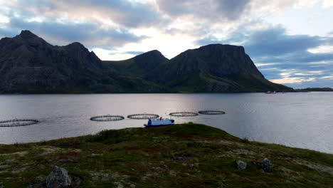 granja noruega de salmón con jaulas marinas circulares, archipiélago de vesteralen en noruega. aerial hacia adelante a baja altitud, hermoso paisaje