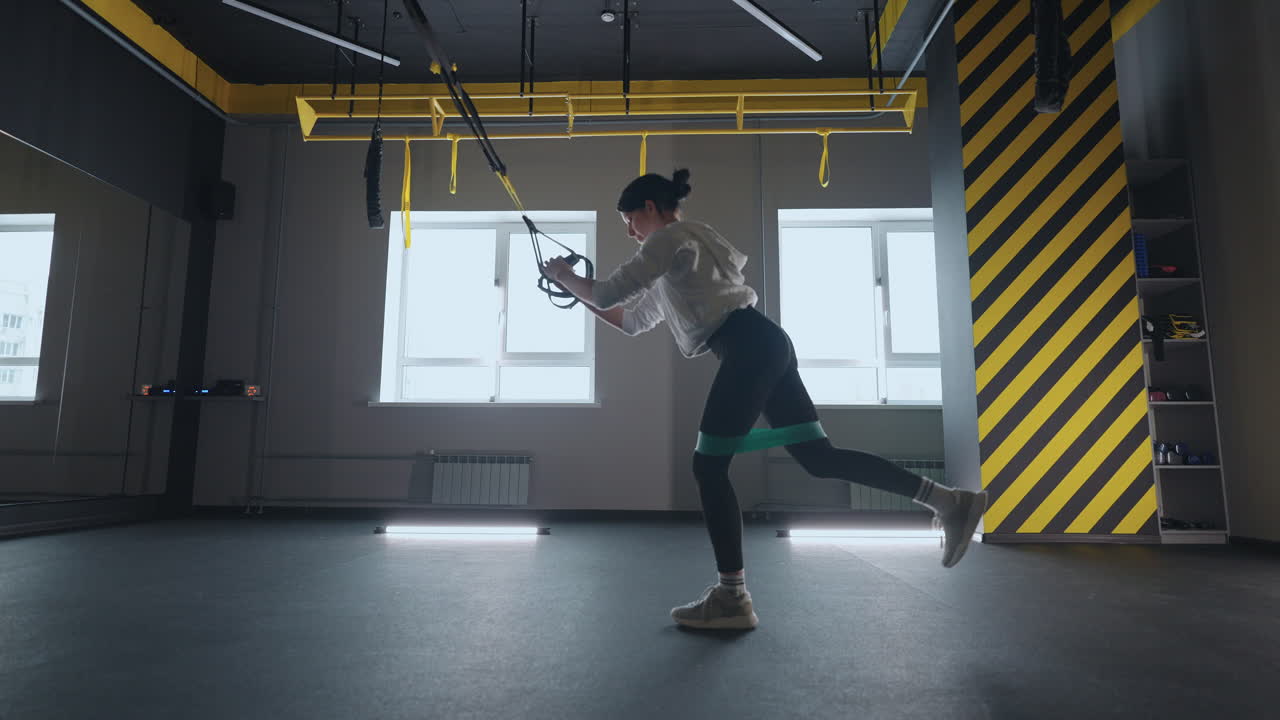 fitness TRX training exercises at gym woman push-up workout. Attractive woman doing exercise for hands in gym. core abs crossfit oblique training with fitness straps in the gym's studio. TRX